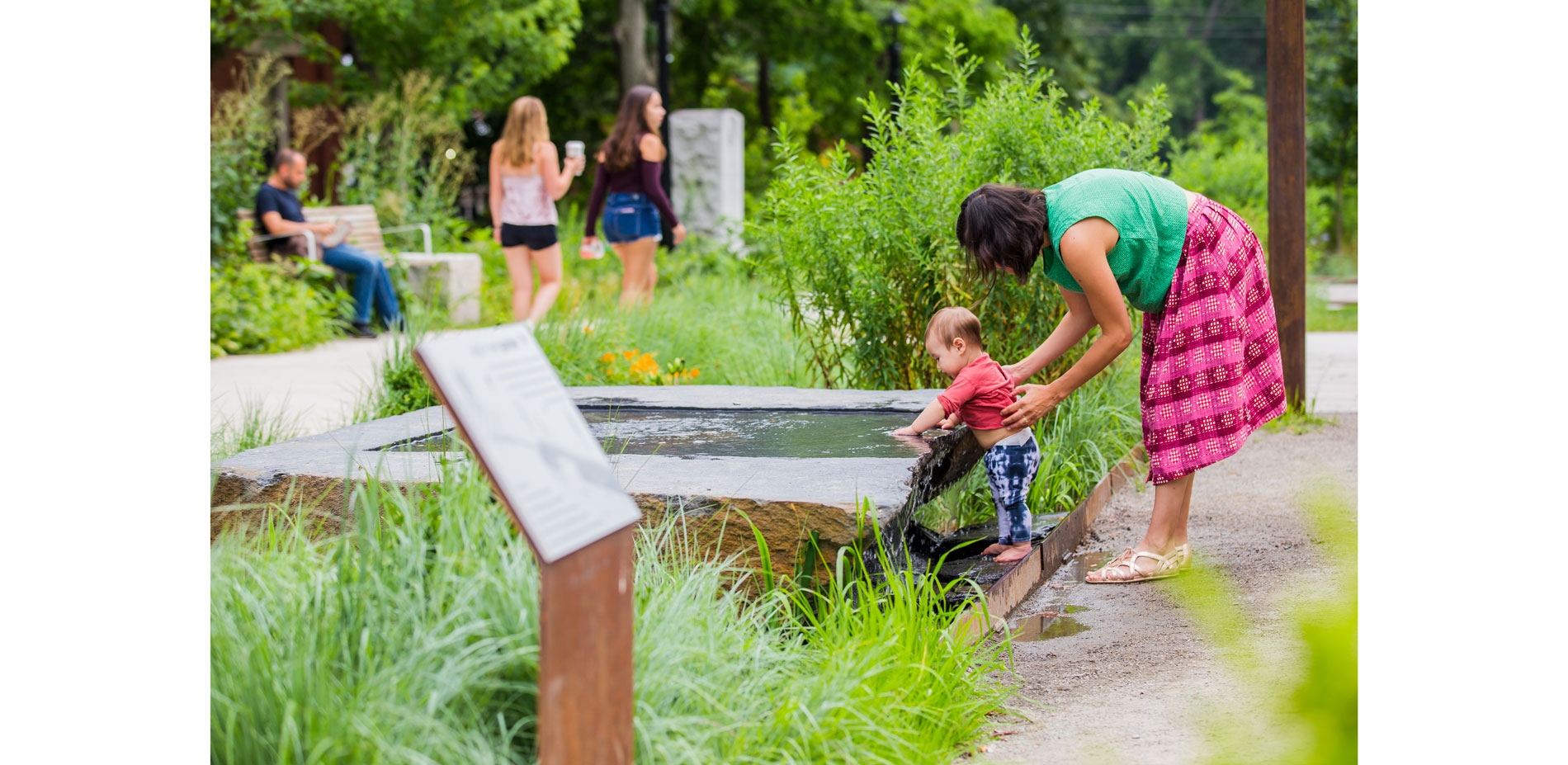 A slab of local Goshen stone defines the edge of the bioswale at the plaza. Carved on-site, it is an interactive feature for children and a watering h…