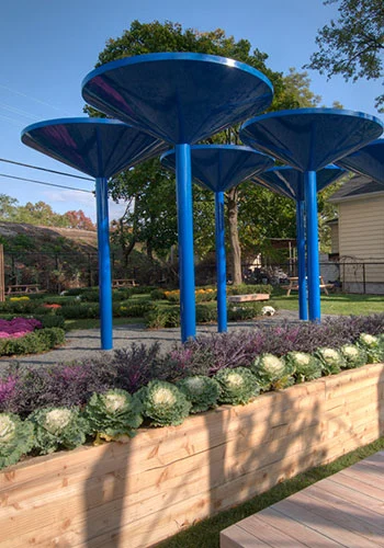 Sculptural rainwater collection towers amidst planting beds at the Curtis "50-Cent" Jackson Community Gardens in Queens, NY / New York Restoration Project