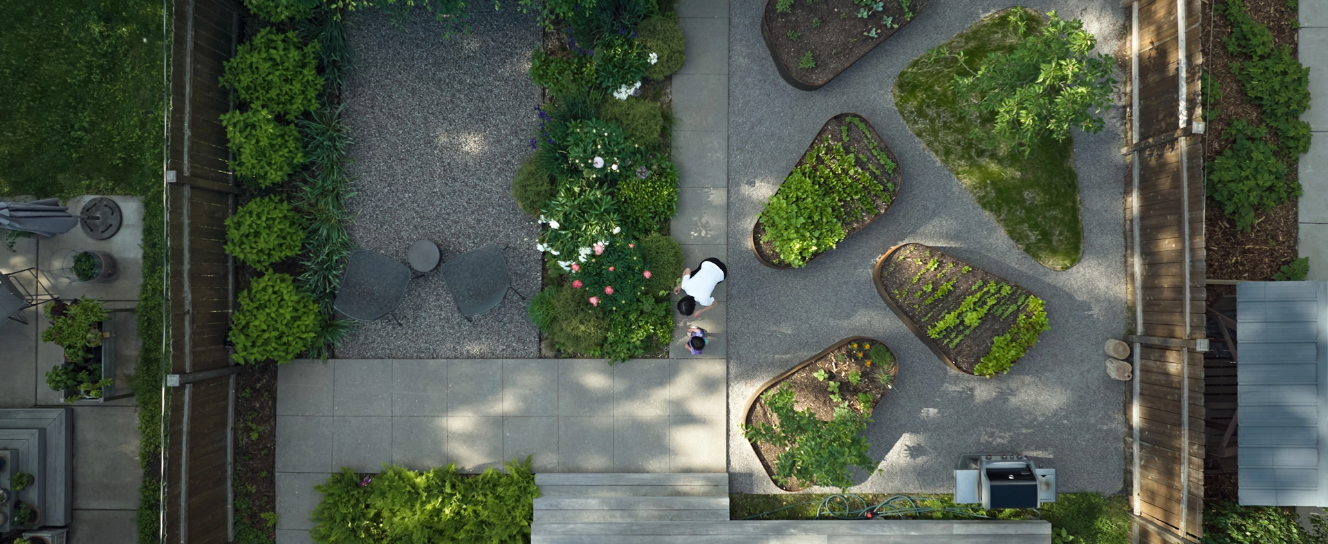 Aerial view of backyard designed as a space for family gatherings, outdoor dining, play, and shared gardening experiences
