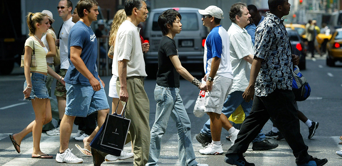 Rear view of many people walking down a city sidewalk