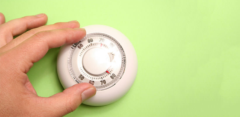 Close-up of a hand adjusting a thermostat